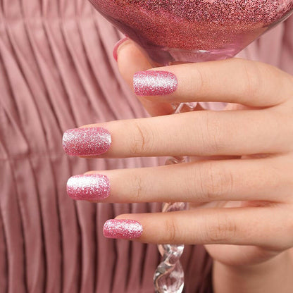 Hand showing pink glitter gel nail wraps with sparkly finish