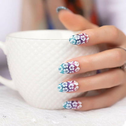 Rainbow ombre hibiscus gel nail wraps on hand holding mug, tropical floral nail art