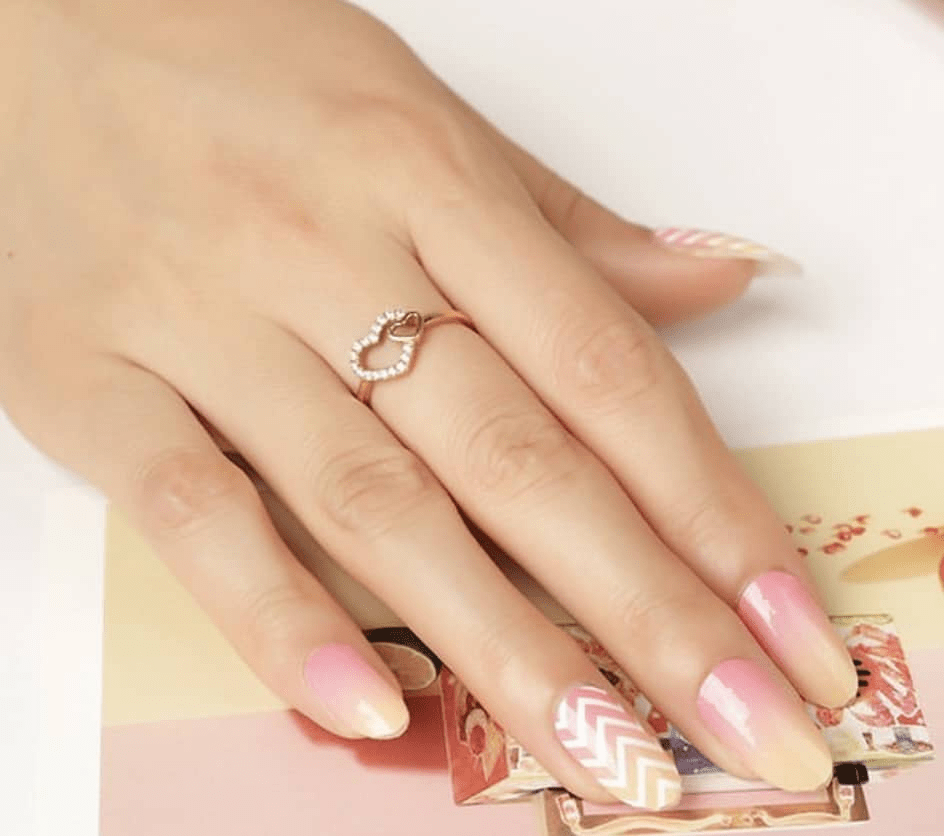 Pink chevron pattern nail wraps on hand with ring showing elegant nail art