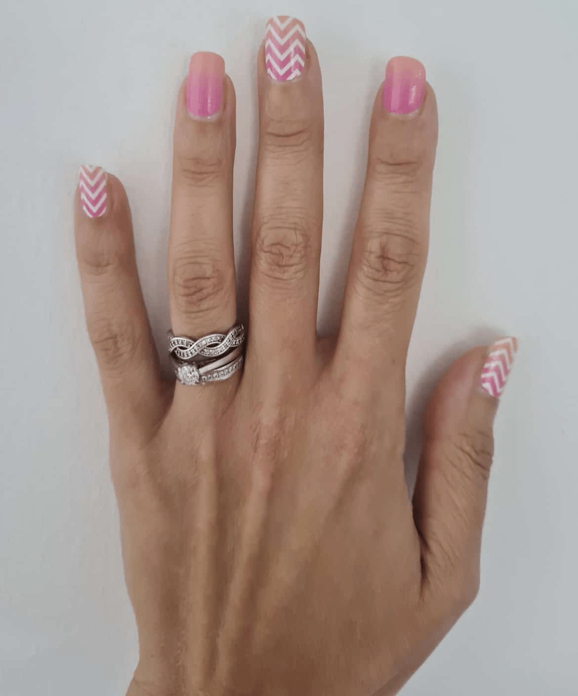 Pink ombre nail wraps with white chevron pattern on hand showing glossy finish