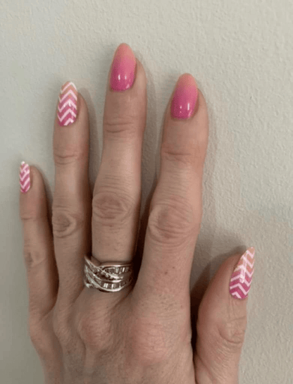 Peach to pink gradient gel nail wraps with geometric chevron design on fingernails