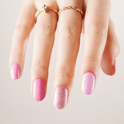Pink gel nail wraps on hand with rose gold glitter accent nail