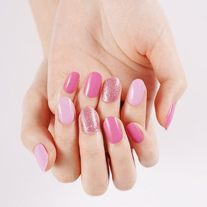 Pink gel nail wraps on hands featuring glitter accent nails and glossy finish