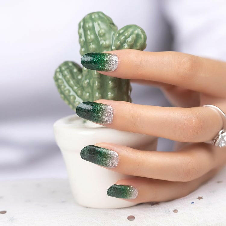 Green gradient nail wraps with silver glitter on hand holding ceramic cactus ornament
