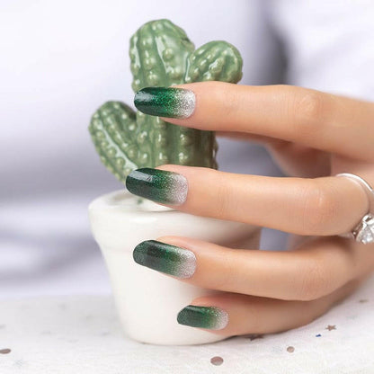 Green gradient nail wraps with silver glitter on hand holding ceramic cactus ornament