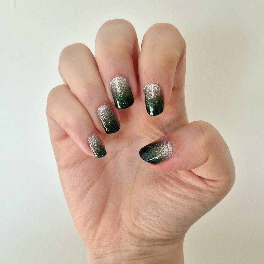Dark green to silver ombre glitter nail wraps displayed on raised hand