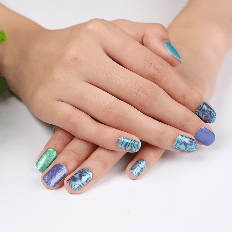 Hands showing blue marble nail wraps with ocean wave patterns at-home manicure