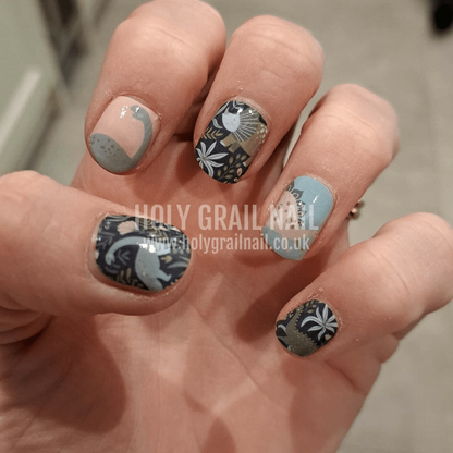 Sage green dinosaur nail wraps on hand featuring prehistoric botanical patterns and glitter accents