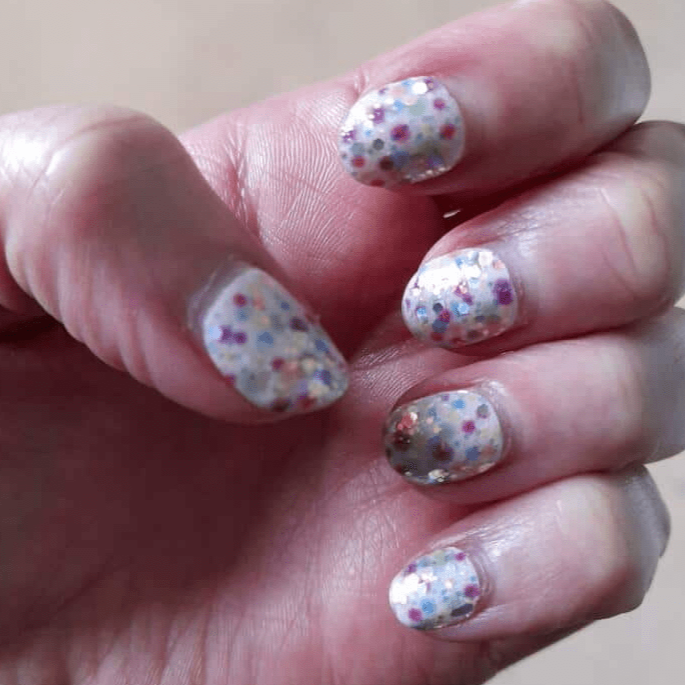 Colourful confetti dot nail wraps on hand showing rainbow bubble pattern manicure