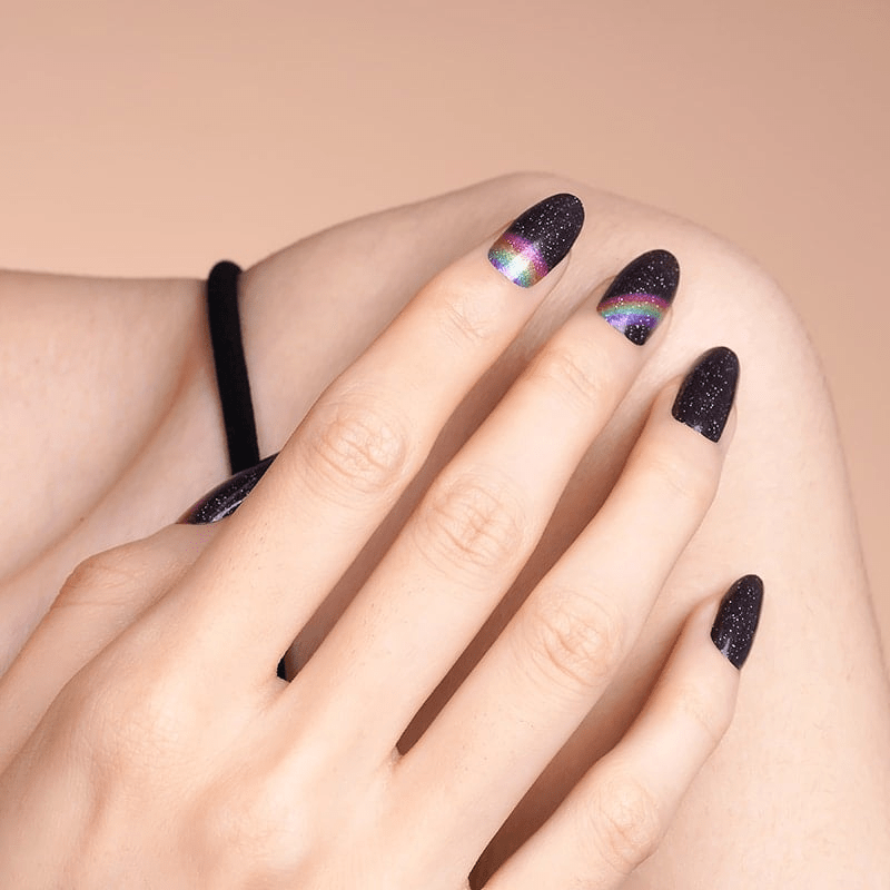 Black glitter nail wraps with rainbow holographic design on hand manicure