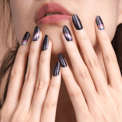 Black glittery nail wraps with rainbow holographic stripes on hands near lips