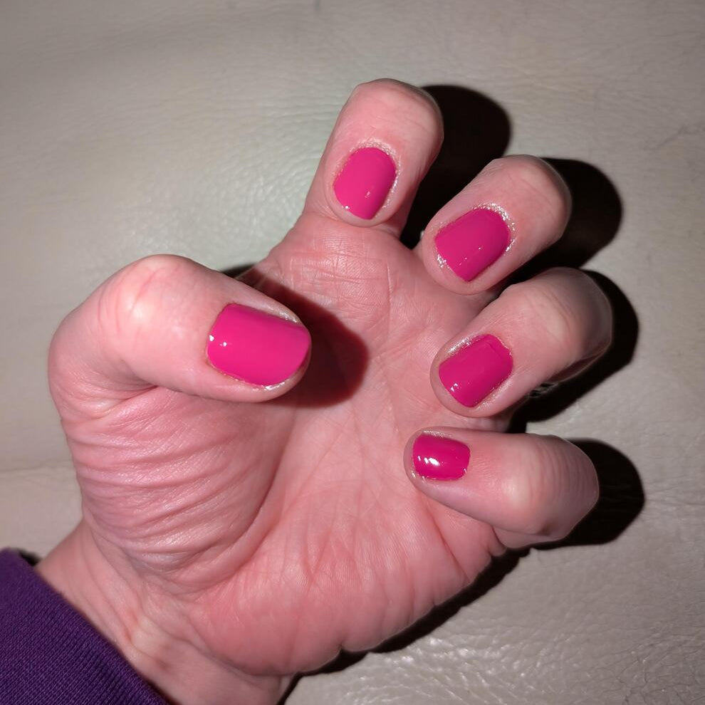 Hot pink raspberry nail wraps applied on hand showing vibrant solid colour manicure