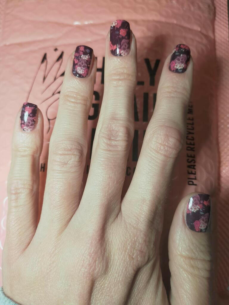 Gothic skull and rose nail wraps applied on hand showing complete manicure