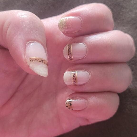 Close up neutral nail wraps featuring gold metallic leopard print nail art design