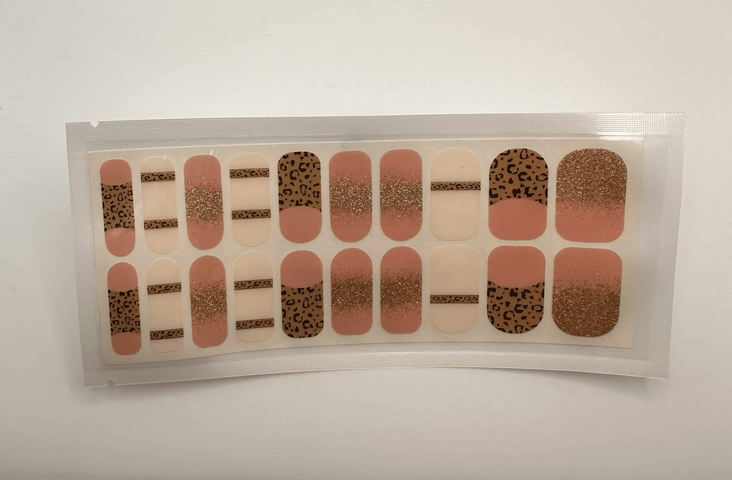 Nude and leopard print nail wraps with gold glitter accents in wide fit packaging