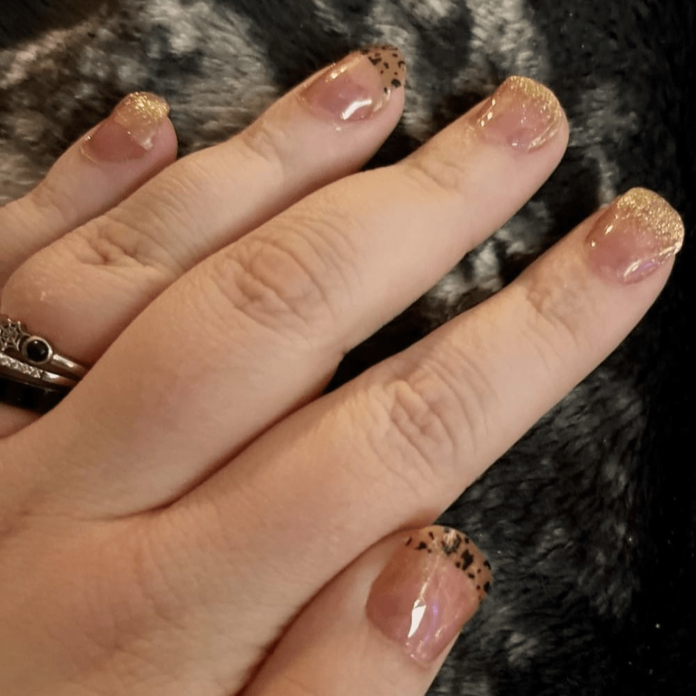 Hand showing pink gel nail wraps with gold glitter leopard print pattern