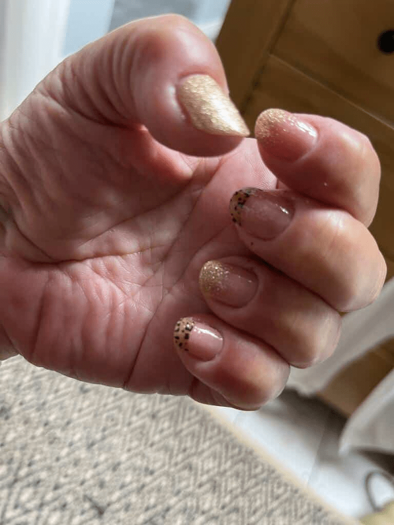 Cupped hand displaying nude nail wraps with metallic gold animal print accents