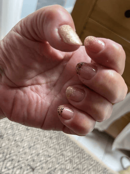 Cupped hand displaying nude nail wraps with metallic gold animal print accents