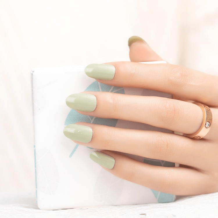 Hand with sage green matte nail wraps in natural light for at-home manicure