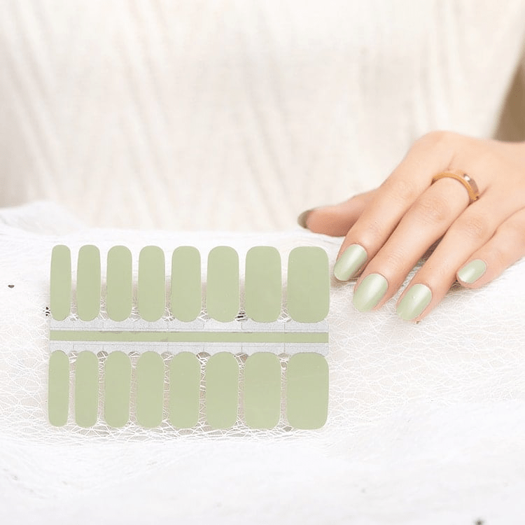 Sage green nail wrap sheets with hand showing applied matte finish manicure