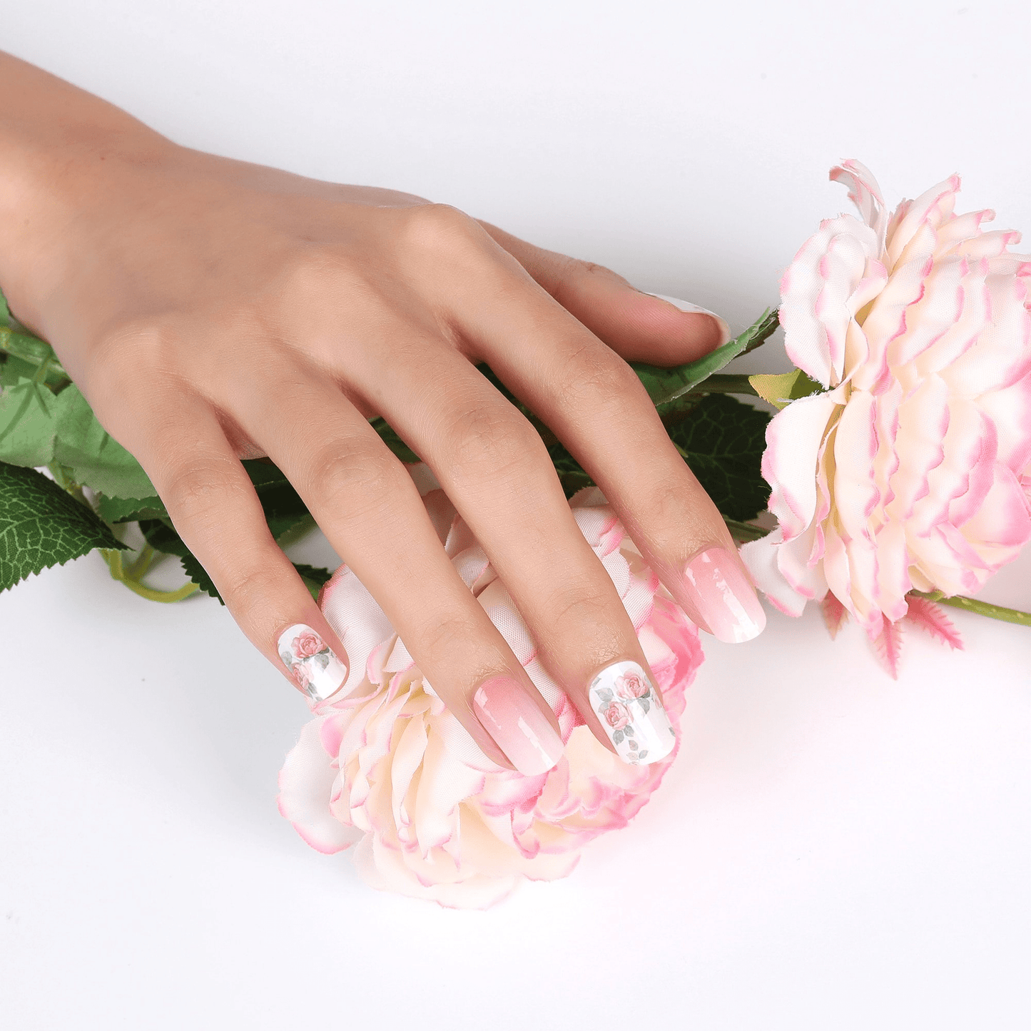 Hands with pink rose floral nail art wraps surrounded by flowers