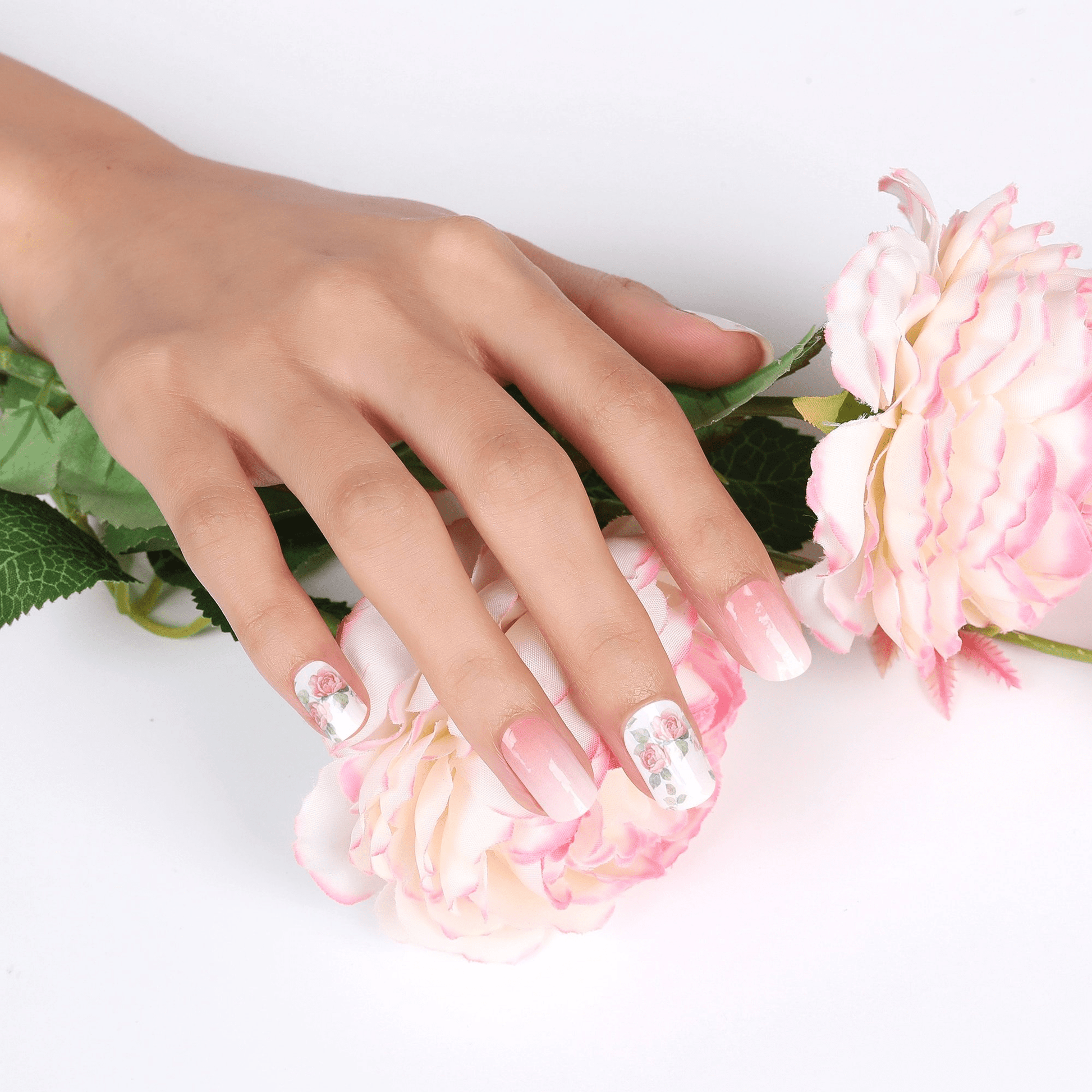 Hands with pink rose floral nail art wraps surrounded by flowers