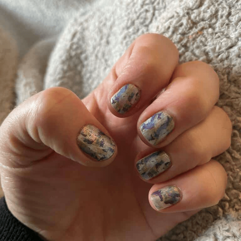 Hand wearing watercolour nail wraps with artistic blue green abstract floral pattern