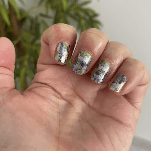 Hand displaying artistic watercolour gel nail wraps with blue green paint effect design