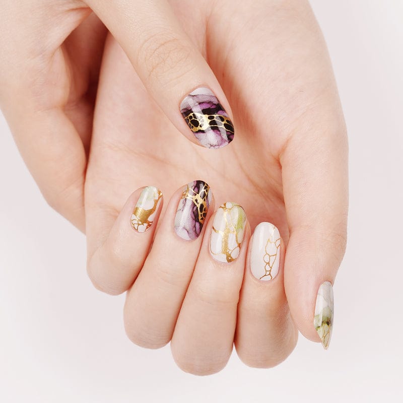 Manicured hand showing marble nail wraps in mauve and sage green with gold veining