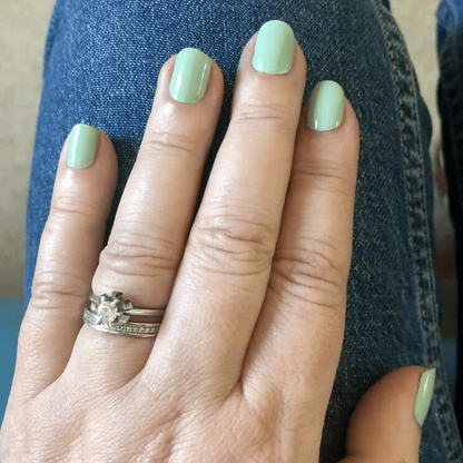Sage green glossy nail wraps on hand showing muted pastel manicure