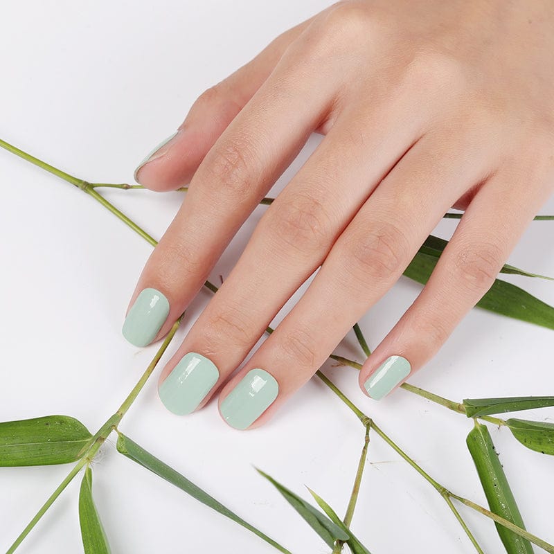 Sage green nail wraps on hand with botanical leaves for natural manicure look