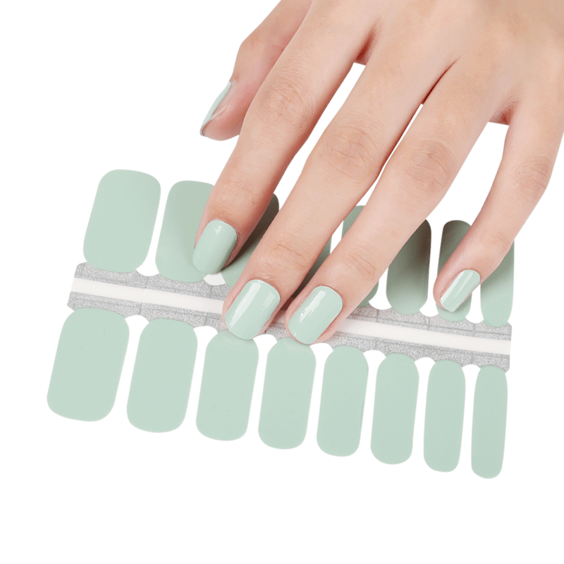 Sage green nail wrap strips being applied showing DIY at-home manicure process