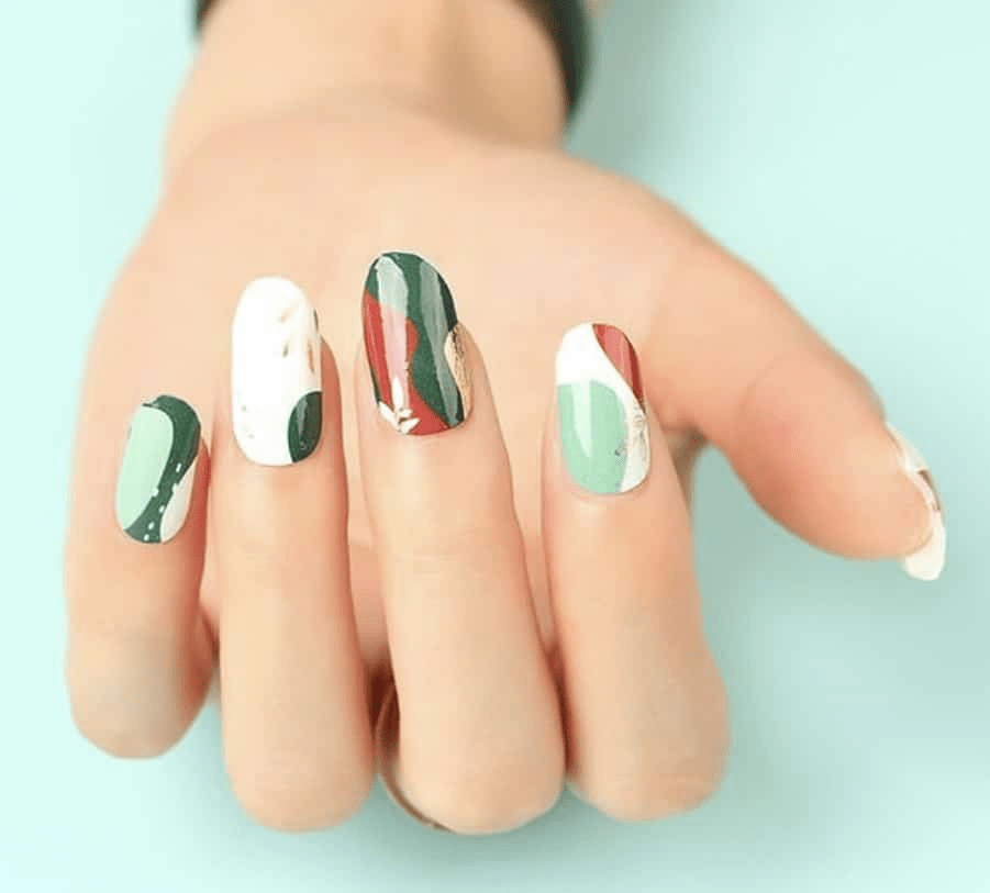 Hand wearing sage green and rust botanical nail wraps with leaf designs