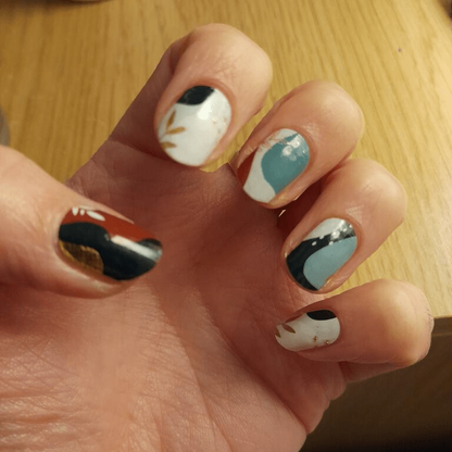 Botanical nail wraps in sage and russet tones with leaf pattern on hand
