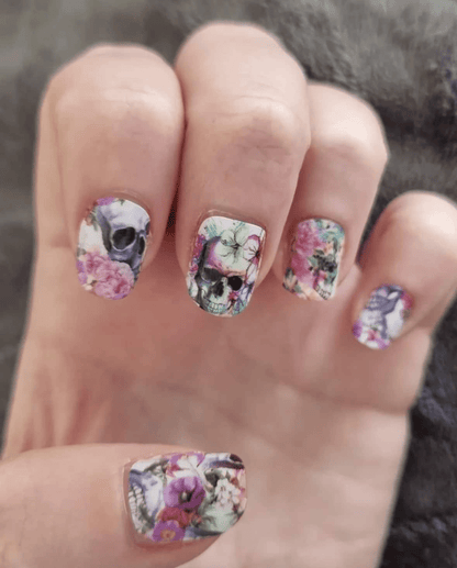 Gothic nail wraps with pink roses and skulls on hands showing edgy floral nail art