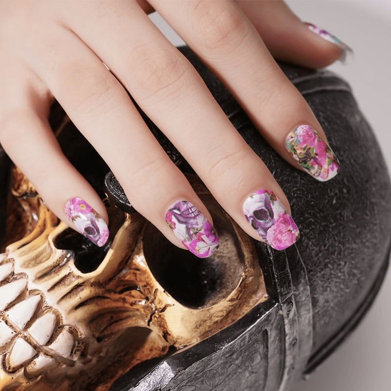 Alternative nail wraps featuring skull and pink rose design on hands for gothic manicure