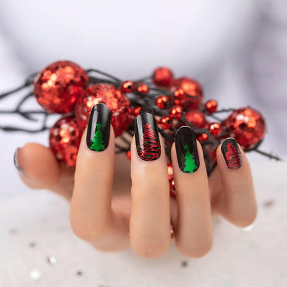 Festive Christmas nail wraps on hand featuring green and red glitter designs with holiday patterns