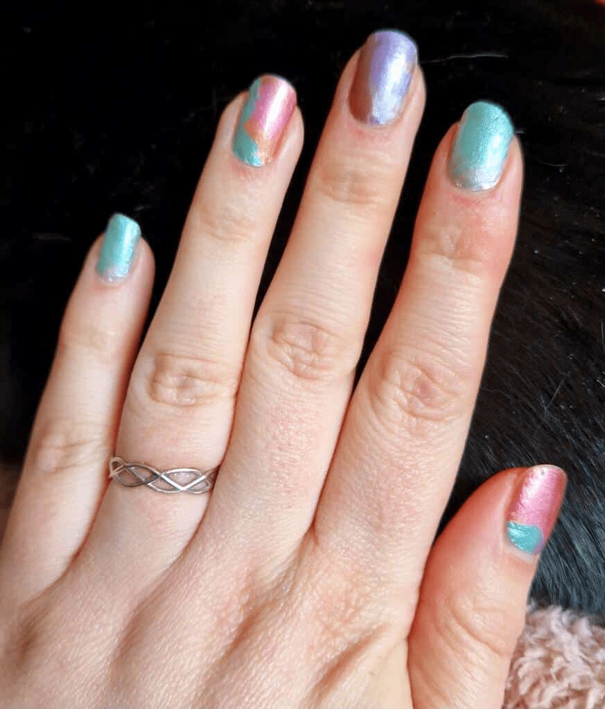Hands displaying iridescent nail wraps with holographic pink and teal colour-shifting effects