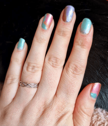Hands displaying iridescent nail wraps with holographic pink and teal colour-shifting effects