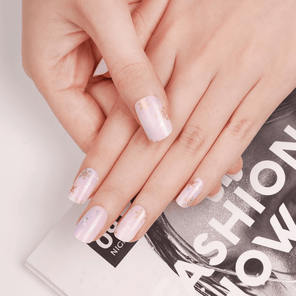Hands displaying finished pink snowflake nail wraps manicure with winter nail art design