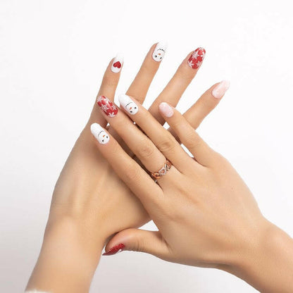 Two hands displaying festive Christmas nail art with red snowflake and white snowman wraps