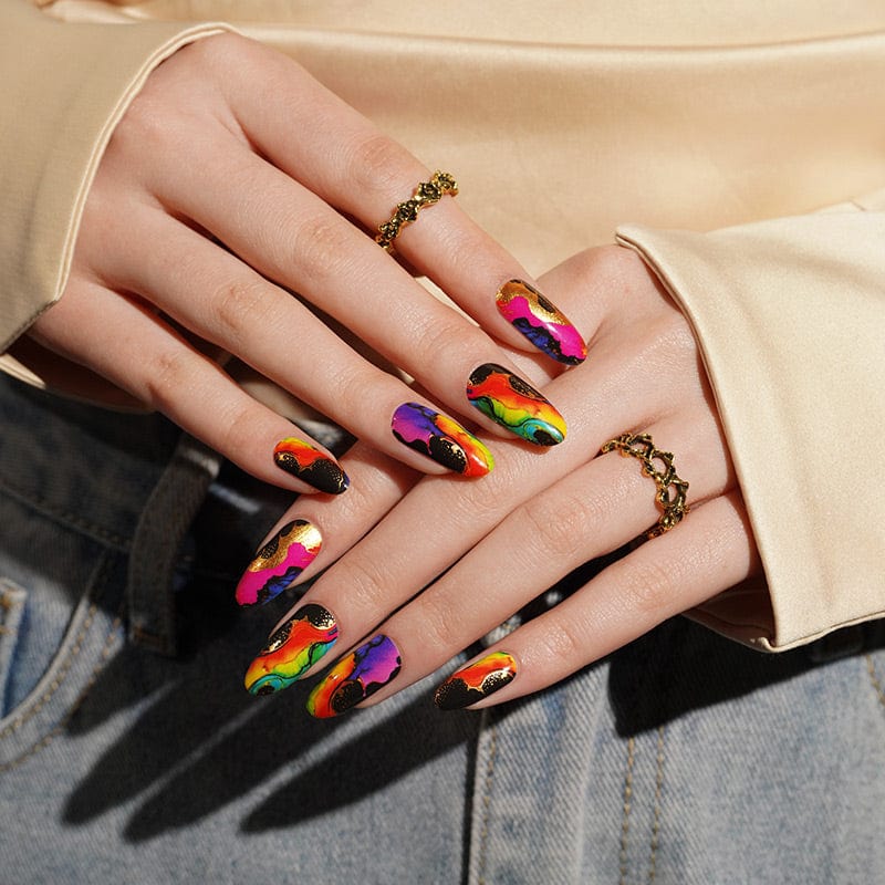 Bold abstract nail wraps on manicured hands showing bright multicolour artistic patterns in neon pink, blue and orange