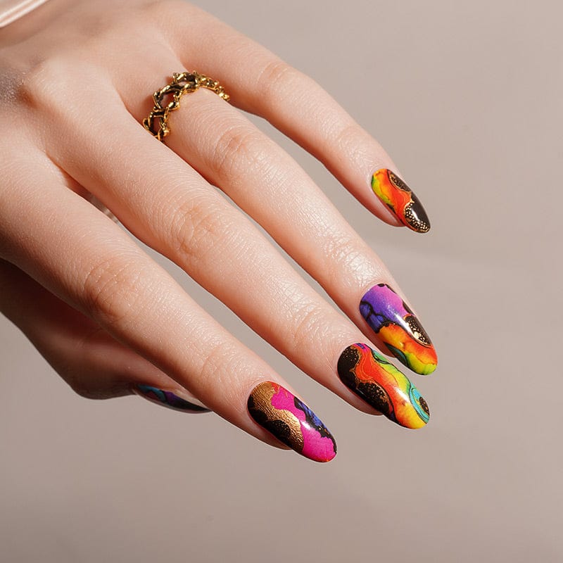 Colourful abstract nail wraps on hand featuring vibrant multicolour patterns with neon pink, orange, blue and gold designs