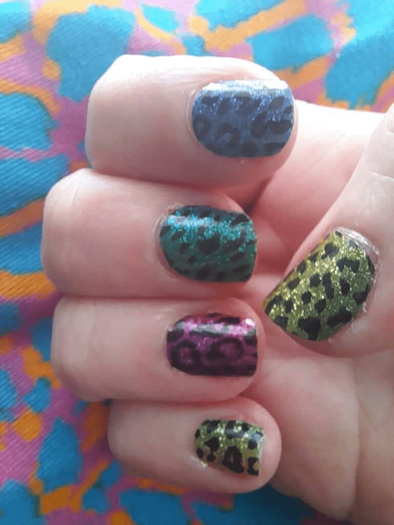 Glittery leopard print nail wraps on hand with vibrant multicoloured animal print patterns