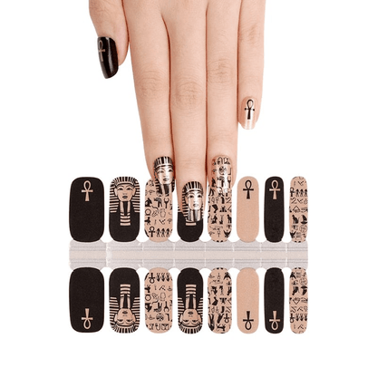 Egyptian themed nail wraps with black and gold pharaoh sphinx patterns displayed on hand
