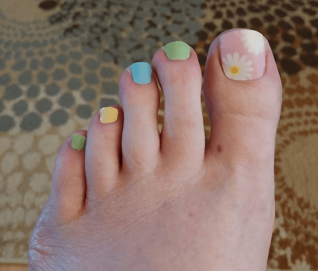 Pastel non-UV pedicure wraps on toes featuring rainbow colours and daisy nail art