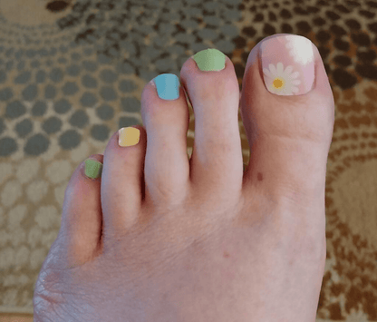 Pastel non-UV pedicure wraps on toes featuring rainbow colours and daisy nail art