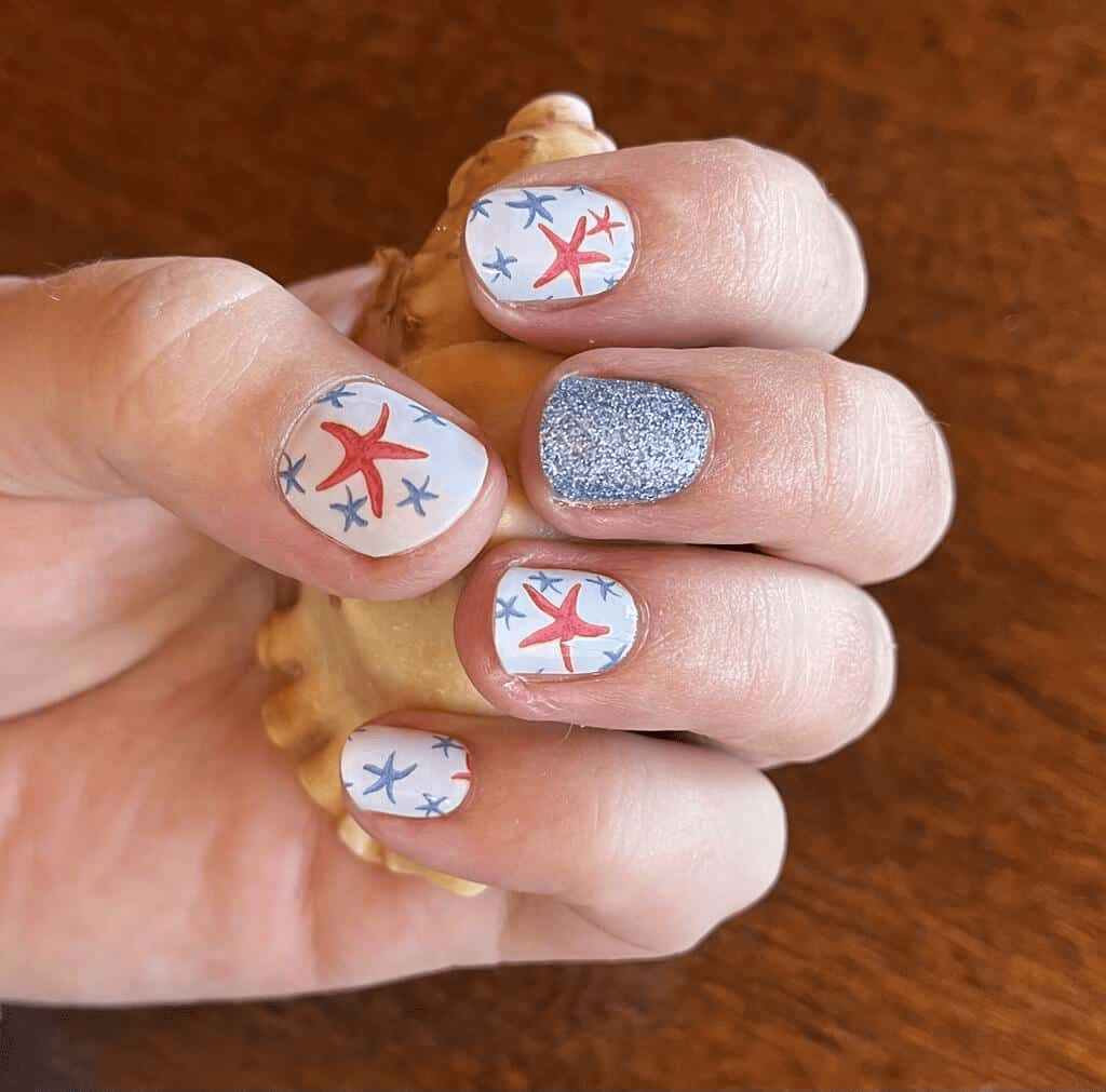 Clenched fist showing nautical starfish nail art wraps with sparkly blue glitter nail