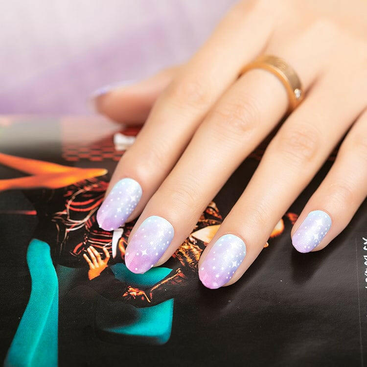 Hand with ombre nail wraps featuring white polka dots on pink blue gradient