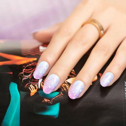 Hand with ombre nail wraps featuring white polka dots on pink blue gradient